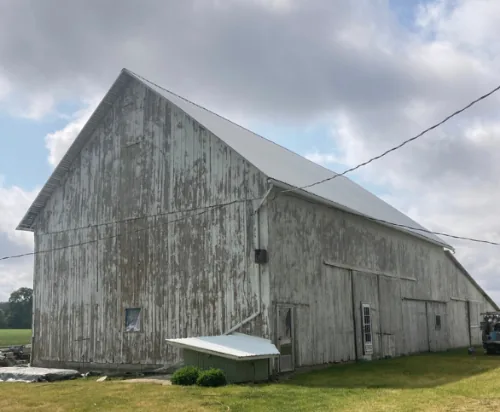 Barn before: gray, weathered siding with most of the old paint worn away