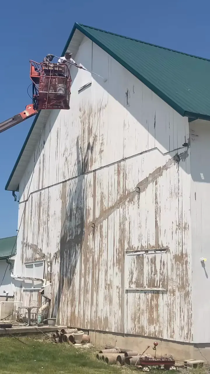 A lift raised against the gable of a weathered barn during a job
